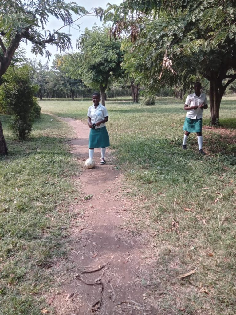 Students relaxing on the green school compound at Muhokya Parents Secondary School in Kasese.